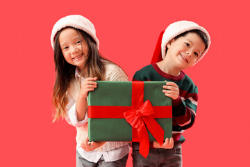 Cute little children with Christmas gift on red background