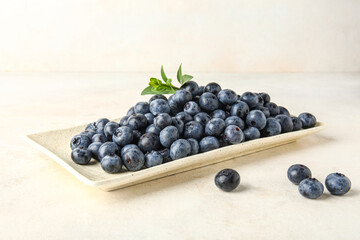 Plate with fresh blueberries on white background