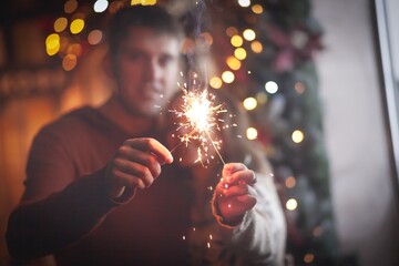 Beautiful couple holding sparklers celebrating christmas. Happy holiday - obrazy, fototapety, plakaty