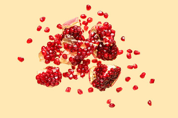 Flying fresh pomegranates with seeds on yellow background