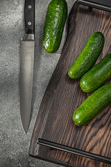 Cucumbers And kitchen Knife On Stilized kitchen Board.