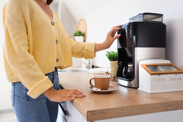 Woman using coffee machine in kitchen