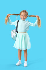 Cute little girl with backpack on blue background