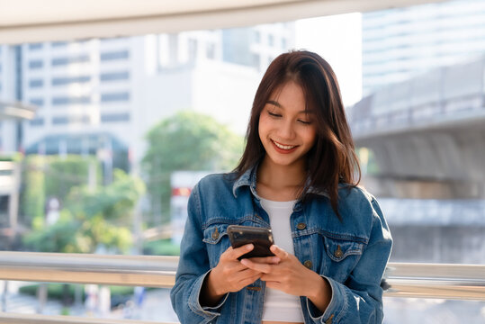 Young asian woman standing and using smartphone on the street