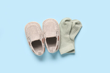 Stylish baby shoes with socks on blue background