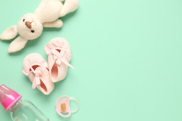 Stylish baby shoes with bottle of milk, pacifier and cute toy on turquoise background