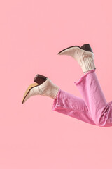Legs of young woman in stylish beige leather boots on pink background