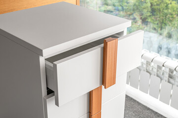 Stylish white office commode with wooden handles and legs with open empty drawers closeup view. Comfortable furniture for home and office furnishing - 681334259