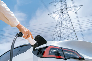 Closeup woman recharge EV electric car battery at charging station connected to electrical power...