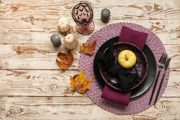 Autumn table serving with pumpkin, dry leaves and folded napkin on white wooden table