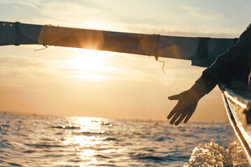 Silhouette of a hand from a boat on a sunset background