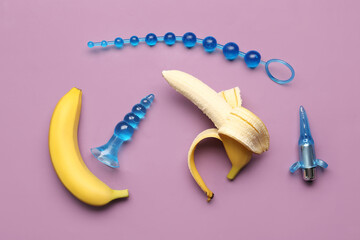 Anal plugs from sex shop and tasty bananas on purple background