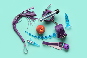 Different sex toys and tasty peach on turquoise background