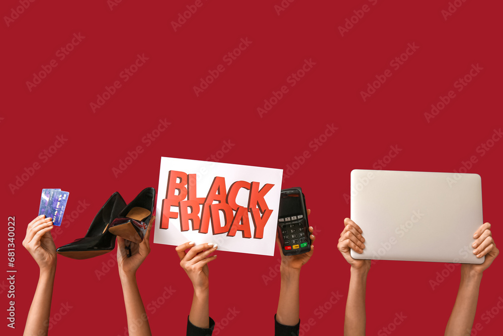 Wall mural Female hands holding poster with text BLACK FRIDAY, shoes, credit cards, laptop and payment terminal on red background