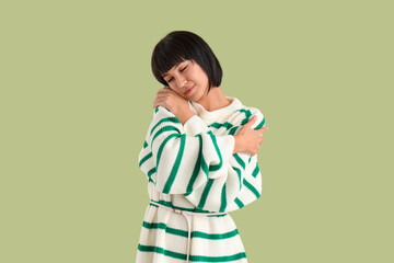 Young woman hugging herself on green background