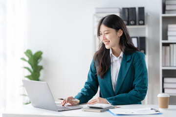 Smiling asian businesswoman using laptop computer at office. Confident Asia businesswoman sitting happily in the office.