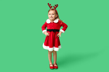 Cute little girl in Santa Claus costume on green background