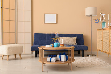 Interior of festive living room with blue sofa and decorations for Hanukkah celebration on coffee...