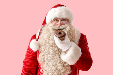 Santa Claus eating tasty donut on pink background