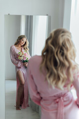 a beautiful woman with flowers stands in front of the mirror