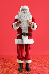 Santa Claus with glass of beer and tasty french fries on red background