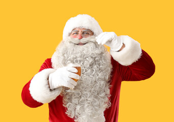 Santa Claus with glass of beer on yellow background