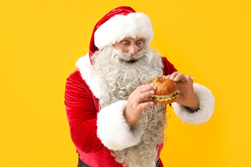 Shocked Santa Claus with tasty burger on yellow background