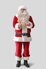 Santa Claus with tasty donut showing thumb-up on white background
