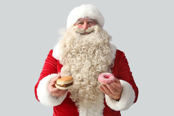 Santa Claus with tasty donut and burger on white background