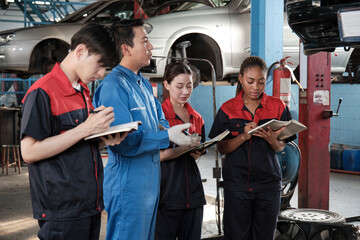 Specialist lecture. Male supervisor engineer describe automotive suspension fixing with mechanic worker staff teams for repair work at car service garage and maintenance jobs in automobile industry. - obrazy, fototapety, plakaty