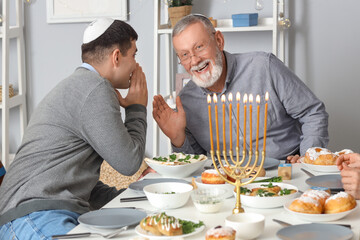 Mature man having dinner with his son at home on Hanukkah