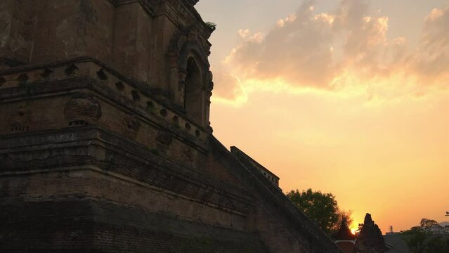 Wat Chedi Luang at sunset, clouds catch the colours of the setting sun as the camera pans down to show the huge structure.