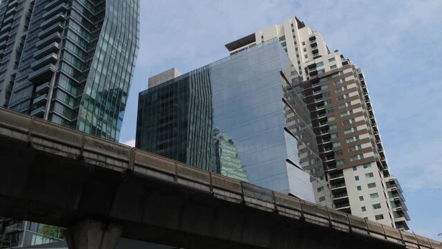 A building on Sukhumvit street with the BTS elevated railway, blue sky and clouds, Bangkok, Thailand