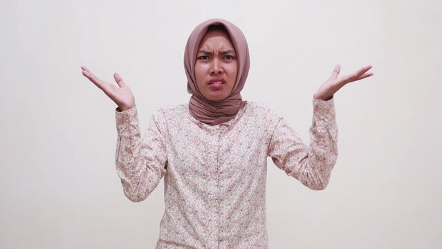 Confused young asian muslim girl standing between two choice and showing puzzled face expression gesture
