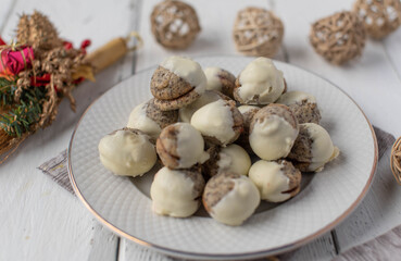 Christmas cookies with jam filling, poppy seeds. Covered with white chocolate on a white plate 