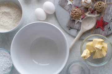 Christmas baking background with kitchen utensils and ingredients sauch as flour, butter, eggs, bowl, wooden spoon . Top view