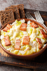 Scandinavian plukkfisk is made with lightly salted cod over mashed potatoes, topped with tasty bacon close up on a plate on the table. Vertical