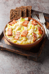 Norwegian Spring Cod Plukkfisk with boiled potato, leek, bacon and bechamel sauce close up on a plate on the table. Vertical