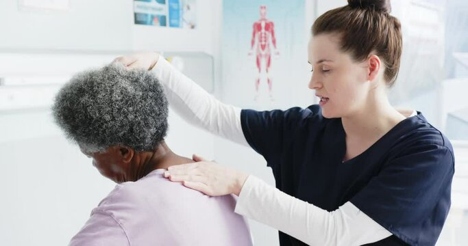 Diverse senior woman exercising neck and female doctor advising in hospital, slow motion