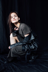Fototapeta na wymiar a woman in dark clothes poses on a black background