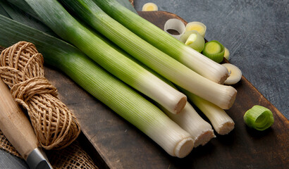Cut fresh leeks on wooden board. Dark background.