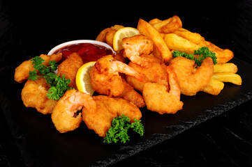 Battered king prawns with chips and parsley herb garnish and tomato sauce dip