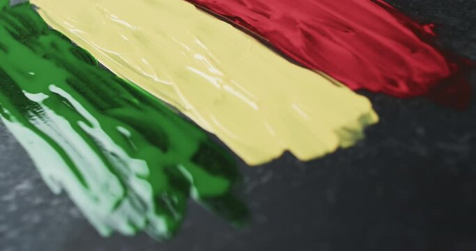 Video of red, yellow and green paint smudges with copy space on black background