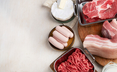 Saturated fats on tables. Raw meat, sausages, cheese, butter. Bad food concept
