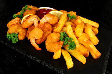 Battered king prawns with chips and parsley herb garnish and tomato sauce dip