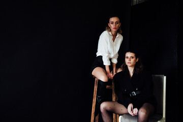 two women pose on a black background