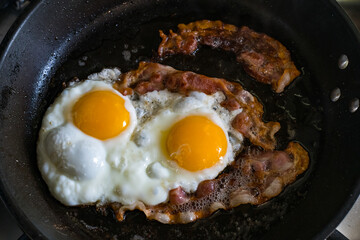 Idea for healthy breakfast two fried eggs and bacon in a pan.