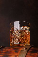 Fototapeta na wymiar Whiskey glass with ice on a rustic barrel, a classic sip