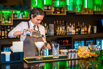 Bartender pouring alcohol in a dispenser to prepare a cocktail