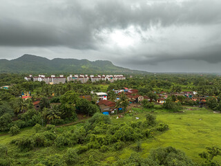 View of Alibag  Village in monsoon season at Konkan, Maharashtra, India. Traditional Indian village house surrounded by green grass and beautiful cloudy blue sky. Village landscape.